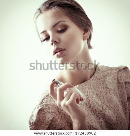 Girl with perfume, young beautiful woman holding bottle of perfume and smelling aroma, toned