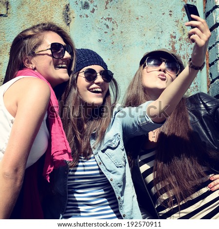 Girls having fun together outdoors and making photo with smart phone lifestyle toned Girls having fun together outdoors and making photo with smart phone lifestyle toned