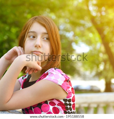 Young girl alone in park, face close up. Toned.