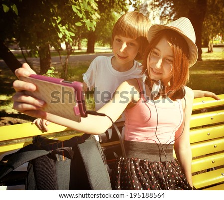 Boy and teen girl have fun outdoor and make photos with smartphone. Toned.