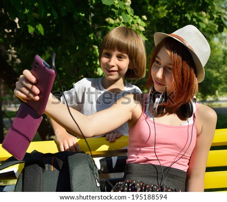 Boy and teen girl have fun outdoor and make photos with smartphone.