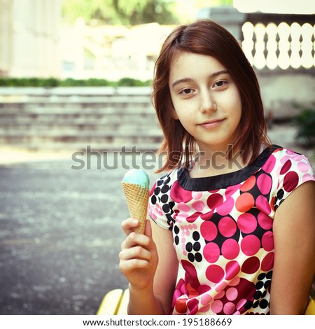 Beautiful teen girl eats ice-cream in the summer park , toned.