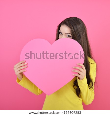 Love and valentines day woman holding heart and smiling over pink background. Beautiful woman in love.