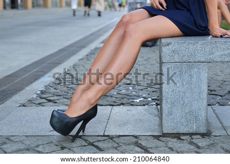 Sexy Female Legs. Fashion Long Legs Blonde Girl Sitting on Bench. Street Fashion. Urban Lifestyle. Young Beautiful Woman Walking Outdoor. Healthcare.