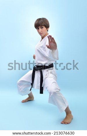 fighting karate girl, young woman with black belts - champions of the world, over blue background studio shot
