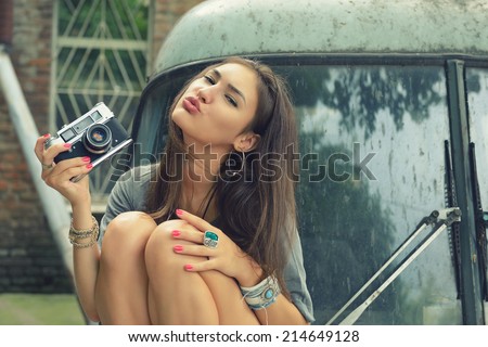 Urban girl has fun with vintage photo cameras outdoor near retro car, image toned.