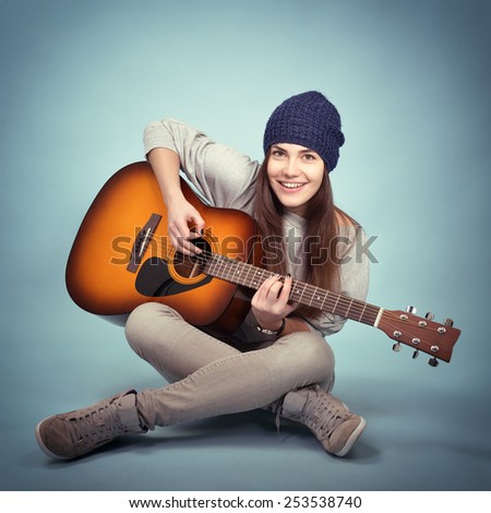 young woman playing music on acoustic guitar, toned