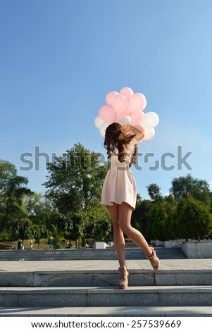 Fashion girl with air balloons steps on stairs