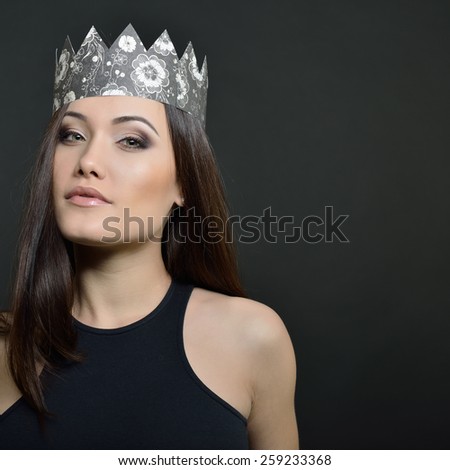 Beauty portrait of young woman with beautiful healthy face and crown, studio shot of attractive girl over black background