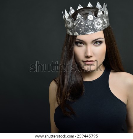 Beauty portrait of young woman with beautiful healthy face and crown, studio shot of attractive girl over black background