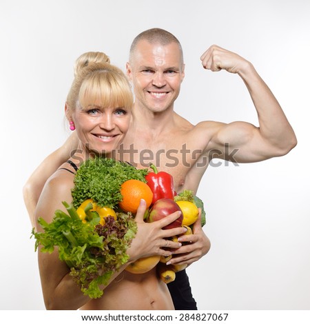 Attractive happy middle-age fit man and woman holding fruit and vegetables. Healthy eating, fitness, diet, vegetarianism and rawfoodist concept.