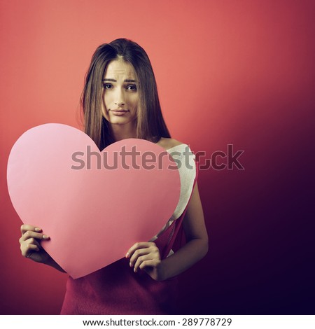 Love and valentines day woman holding heart and smiling over pink background. Beautiful woman in love, image toned.