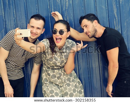 Happy friends taking self photo with smart phone. Selfie, friendship, young adult, happiness, leisure concept. Image toned.
