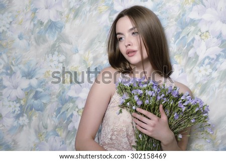 Young beautiful woman holding bunch of wild flowers. Studio shot of attractive girl looking at camera over white background. Toned.