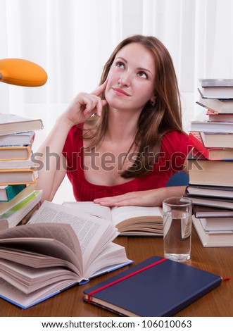 Girl studying at home with lot of books around/Girl learning at the desk/student with books