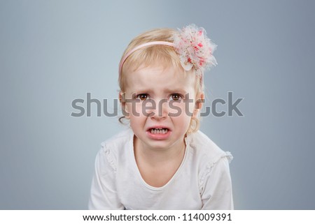 little child is crying. crying girl on grey background. Studio shot