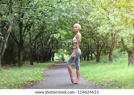 Sporty young woman stay barefoot in park after sport excises.  Yoga woman. Young fit bootless woman in the morning park. Foot free.