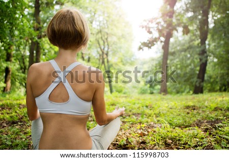 Practicing of yoga outdoors. Young woman In the lotus posture in the sunny forest. Yoga in nature. yoga poses.  Girl from the back.