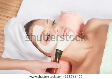 Beautiful young woman having a facial cosmetic mask at spa salon. Girl is having cosmetic treatment.