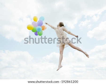 Young slender girl flying in the sky lace dress with bright balloons in her hands