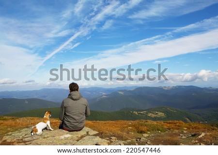 Man and his faithful friend the dog admire the mountain scenery in the campaign