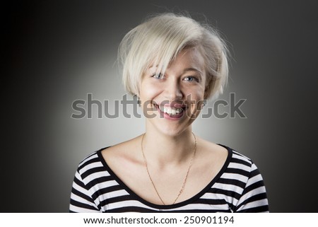 Adorable Stylish blonde with short hair looking into the camera and smiling a big smile with healthy teeth