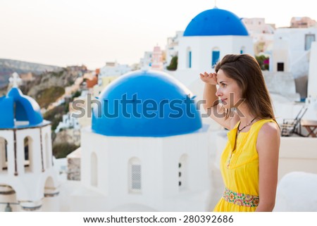 Waiting for fate. girl in a bright yellow dress looks into the sea on the island of Santorini Greece Town Oia