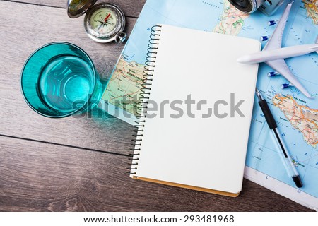 travel , trip vacation, tourism  mockup - close up of compass, glass of water note pad, pen and toy airplane and touristic map on wooden table. Empty space you can place your text or information.