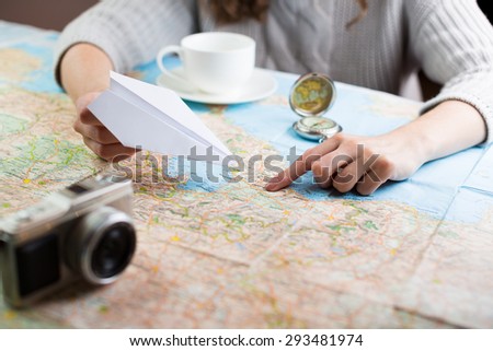 Globetrotter coffee break for trip dreams. Shallow depth of field. woman sitting at table with a map with a paper airplane, compass and camera and visualises his desire to travel