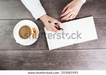 A woman office worker hands writing on empty(blank) book(note, diary) spread mockup, top view, studio. cup of cappuccino break. Empty space in notebook for blog entries, you can place your text