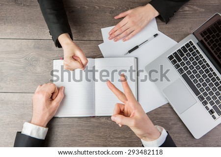 Businessman and businesswoman playing Rock-paper-scissors during the negotiations. Solution controversial conflicts. Top view.  White paper, where you can place your text or information