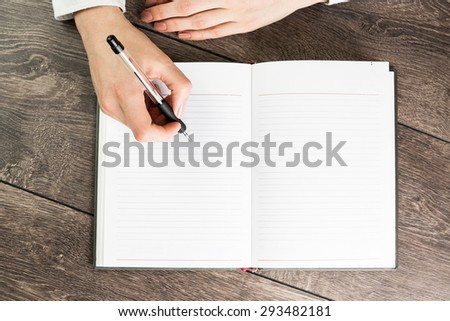 A woman office worker hands writing on empty(blank) book(note, diary) spread(unfold) mockup, top view, studio. Empty space in a notebook for blog entries, you can place your text or information.