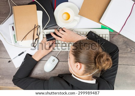 Young beautiful woman lying on the desktop. Fatigue in the workplace. Office modern life. Top view. Working hard