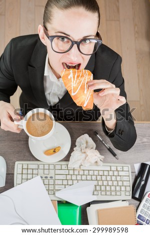 Overhead View Of Businesswoman Working and eating At Computer In Office. Coffee break with croissant