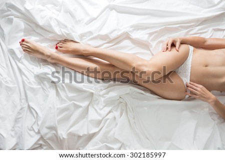 woman lying in bed. long legs, lacy white underwear. beautiful slim figure, gentle morning bliss. white linen sheets