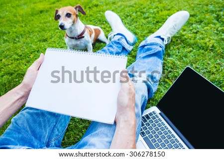 Work outside. Nature and fresh air. Dog and man with white paper note book and pc