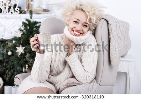 Happy smiling Christmas woman in Knitted stylish clothes. Cozy decorated light holiday interior. Series of winter holiday photos.