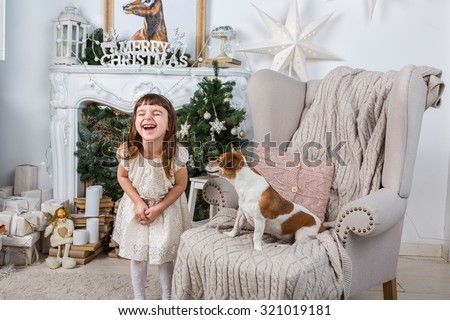 Little girl laughs joyfully laughing, dog, surprised and stares at her. Merry Christmas and Happy New Year interior. A series of photos