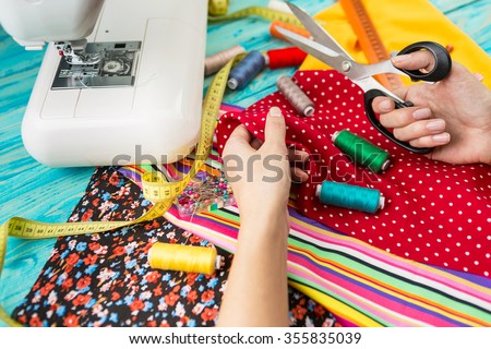 Hands mistress seamstress made a beautiful bright fashionable clothes. The crosslinking parts of the pattern. Work place. Top view. Light Textile industry creative moments