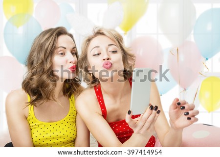 Air kiss. Selfie,  video call over the Internet. Two beautiful woman playful having fun. Pijamas party cool active mood festive atmosphere