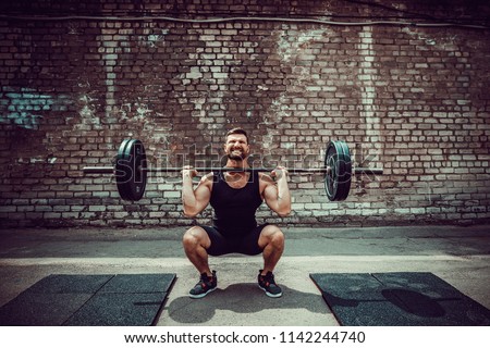 Muscular fitness man doing deadlift a barbell over his head in outdoor, street gym. Functional training. Snatch exercise