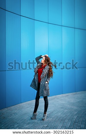 young beautiful girl in a gray raincoat red sweater black pants mess of the shopping center