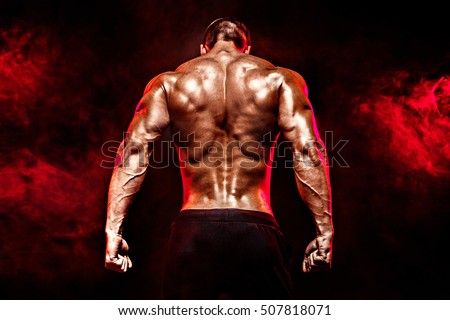 Back view of Unrecognizable man, strong muscles posing with arms down in smoke.
