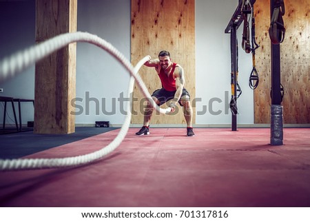 Men with rope in functional training fitness gym in a crossfit workout