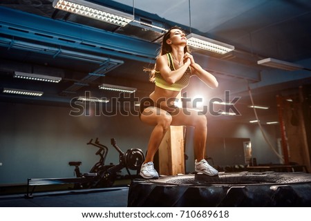 Fit young woman jumping on tire at a crossfit style gym. Female athlete is performing jumps