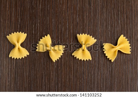 four bow tie pasta on wooden background