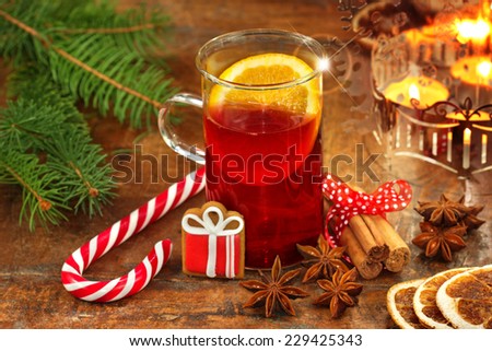 glass of mulled wine, ingredients and candy cane on wooden background