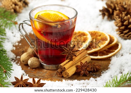 glass of mulled wine, spices and snow on wooden table
