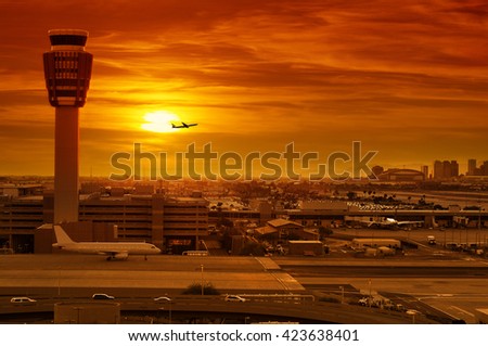 airport control tower and airplane taking off at sunset