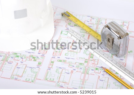Safety headgear, measuring tape and pen on a house plan